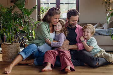 Portrait of young family at home. Pregnant mother with her children and husband in living room.