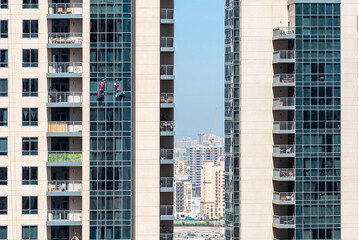Naklejka premium group of climbing workers cleaning a skyscraper window