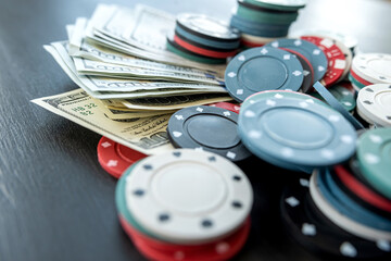 Poker different value chips with dollar bills at black table. Concept of hazard gaming