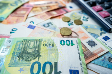 Euro coin and calculator above euro bills. Saving and finance concept