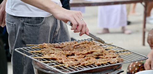 Roast pork on the grill on antique clay stove and wood charcoal burning Traditional pottery at the street food local market in Thailand.