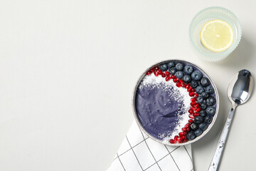 Bowl with smoothie, spoon and glass of water on white background, space for text