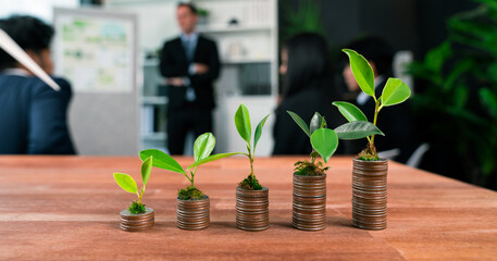 Organic money growth investment concept shown by stacking piles of coin with sprout or baby plant...