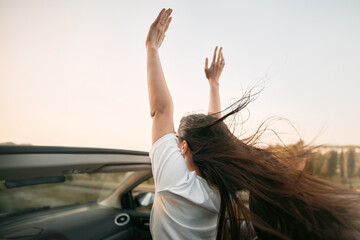 A Happy Woman Enjoying a Summer Road Trip in a Convertible Car. She Raises Her Hands Up in the Air...