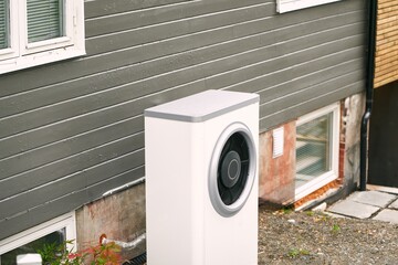 An air conditioner outdoor unit outside of a house in the grass. Modern HVAC and heat pump system