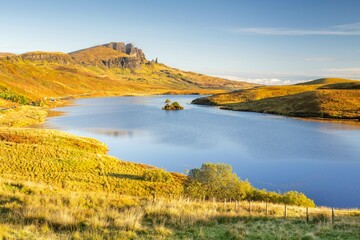 View of rock needle Old Man of Storr, loch with small island in foreground, Isle of Skye, Inner...