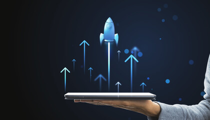 Digital rocket launching from tablet on hand. Online startup and progress concept