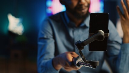 Close up shot of content creator using selfie stick smartphone, doing live broadcast for...