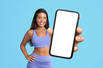 lady in fitwear showcasing large phone with empty screen, studio