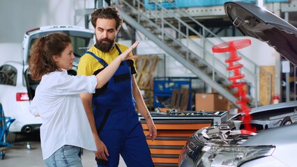Serviceman in car service using holographic augmented reality to show customer defective vehicle piston. Hardworking garage employee using innovative AR tech to project automobile parts for woman