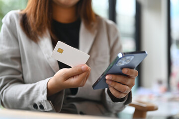 Young woman hand holding credit bank card and using mobile phone for shopping online