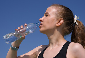 Portrait of young fit fitness athletic woman, happy girl runner drink water outdoors at summer day during running or jogging