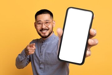 Korean man with large blank cellphone pointing to camera, studio
