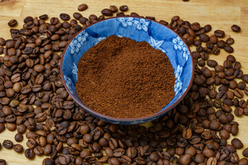 Miseczka pełna zmienionej kawy otoczona ziarnami palonej kawy