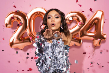 Happy lovely woman send a kiss to camera on pink background with confetti. Happy celebration of new...