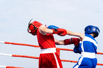 Boxing. Teenagers in the ring during sports competitions. Fight of young boxers in blue and red...