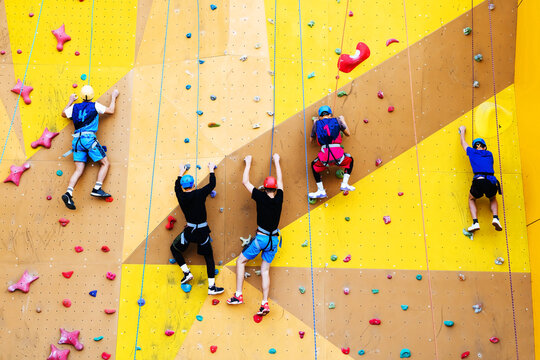 A group of climbers athletes compete in a high-speed ascent of a steep wall. Sports events at the climbing wall. Unrecognizable person