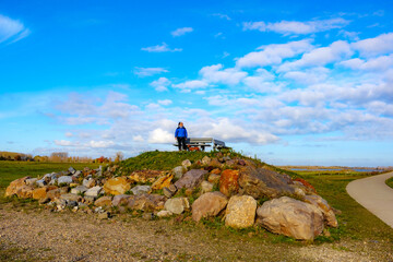 Belgian nature reserve De Wissen with a tourist viewpoint on hill between trails, senior hiker standing admiring landscape next to his dachshund, sunny day with blue sky in Dilsen-Stokkem, Belgium