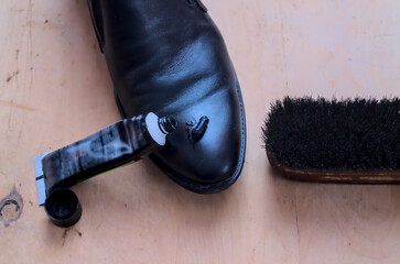 Black leather boot, cream and brush. The concept of shoe care.
