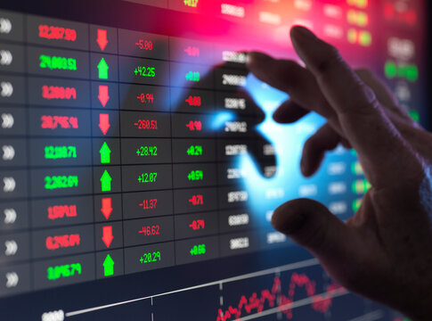Hand of trader examining investment performance data on screen