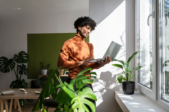Freelancer working on laptop near window at home office