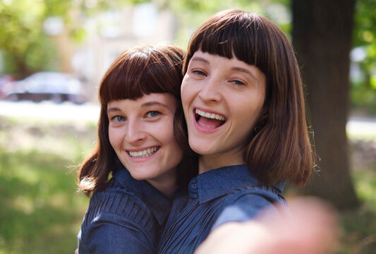 Happy twin sisters taking selfie in park
