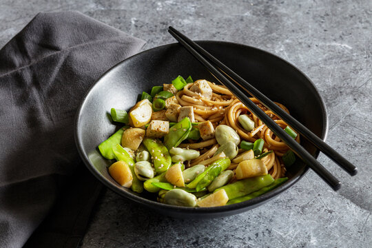 Bowl of vegan miso udon bowl with tofu, snap peas, broad beans and turnips