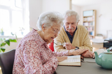 Senior man with woman reading book and holding hands at table