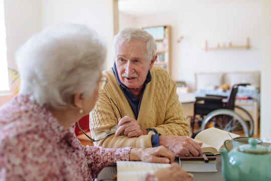 Senior man talking to woman sitting at table