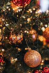 Golden red glossy Christmas ball hanging on a Christmas tree with magic garland lights. Decorated...