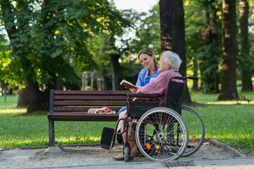 Happy healthcare worker with senior woman sitting in wheelchair at park