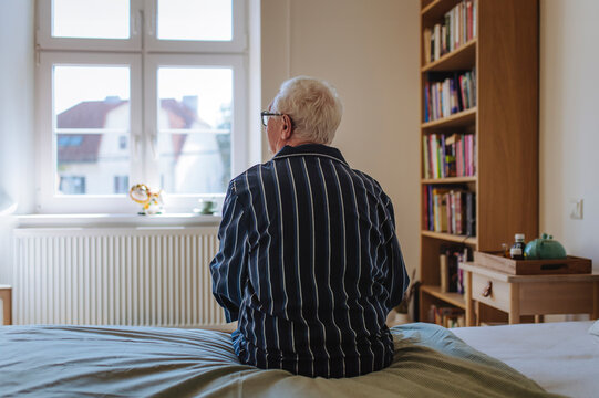 Contemplative senior man sitting on bed at home