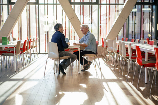 Businessman discussing with colleague at table in cafeteria