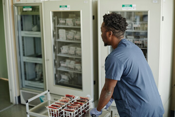 Lab technician pushing trolley of blood bags