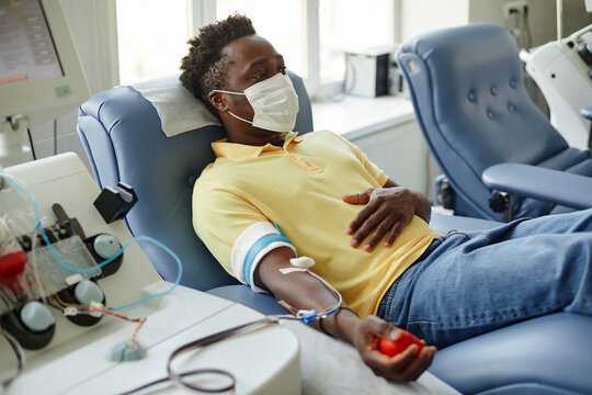 Man wearing protective face mask donating blood