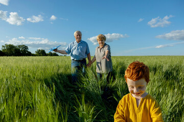 Senior couple spending leisure time with grandson in field