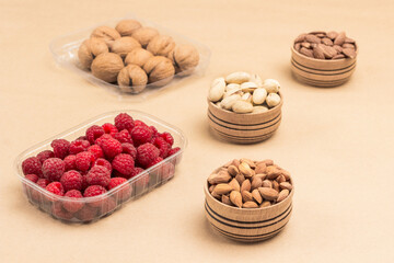Raspberries and walnuts in plastic containers. Nuts in wooden boxes.