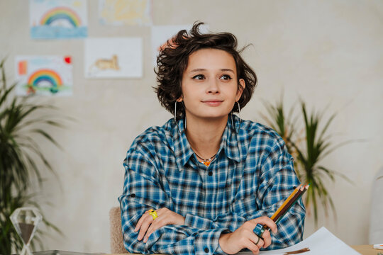 Contemplative graphic designer holding colored pencils at office