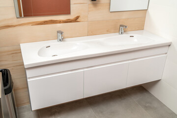 Wall mounted bathroom vanity cabinet with double white porcelain sink and silver sensor faucets in...