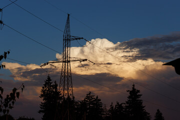 Cloudy and colorful sky with pine trees silhouettes and power lines at golden hour