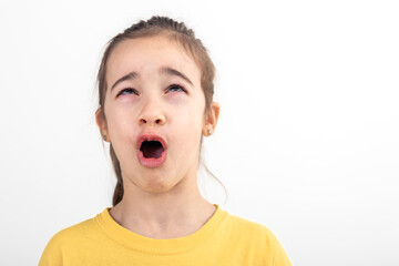Little girl looks to the side in surprise on a white background isolated.