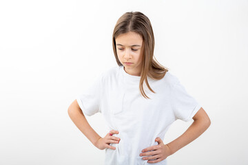 Fototapeta premium A girl in a white T-shirt on a white background holds her hands on her waist.