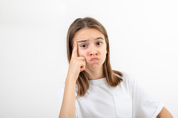 Fototapeta premium Little girl thinking, holding finger at temple, isolated on white background.