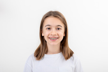 Brunette girl smiling with braces on her teeth on a white background isolated. - obrazy, fototapety, plakaty