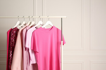 Obraz premium Rack with different stylish women`s clothes near white wall, space for text