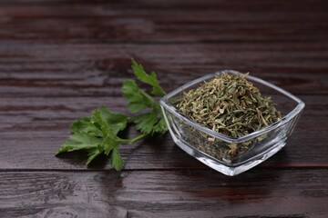 Dried aromatic parsley and fresh leaves on wooden table, space for text