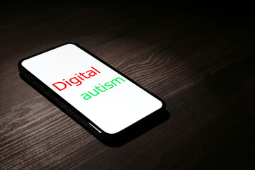 Smartphone with phrase Digital Autism on wooden table, space for text. Addictive behavior