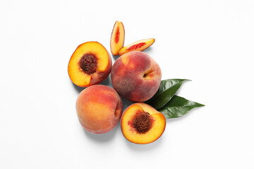 Cut and whole fresh ripe peaches with green leaves on white background, flat lay