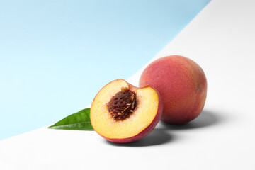 Delicious juicy peaches and leaf on color background