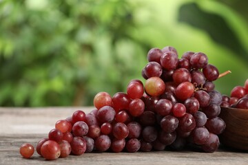 Delicious fresh red grapes on wooden table against blurred background, closeup. Space for text